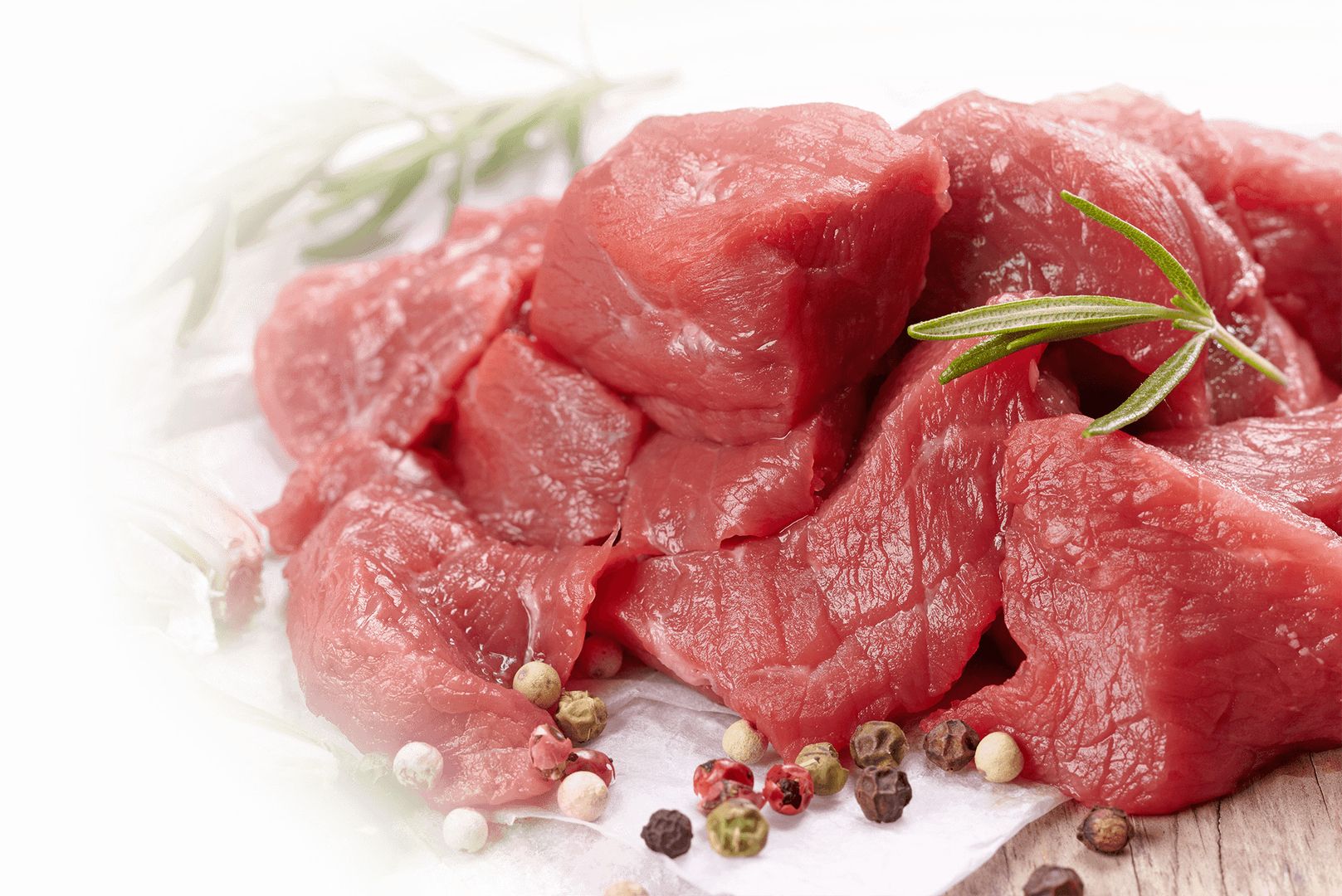 Auf einem Schneidebrett liegt rohes Rindfleisch, dekoriert mit verschiedenen Kräutern.